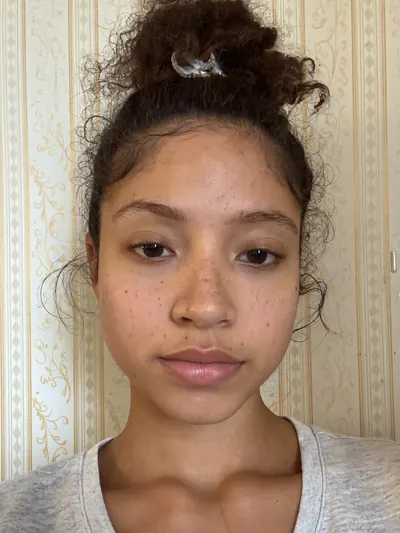 Selfie: curly hair in a bun, freckles across both cheeks.
