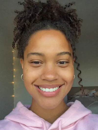 Selfie: curly updo, pink hoodie, a wide smile.