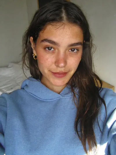 Selfie: messy dark hair, gold hoops, a pink nose and cheeks.