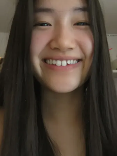 Selfie: long dark hair, a big gap-tooth smile, fairy lights.