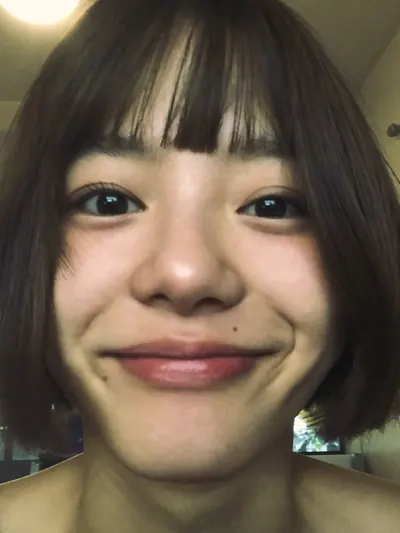 Close-up selfie: a bob with bangs, warm indoor light.